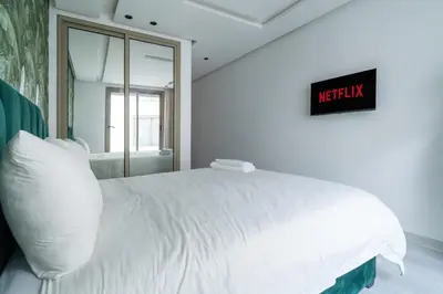 a white bed in a bedroom with a sign on the wall at Maarif Premium 2 Bedrooms 2 Bathrooms La Reine II in Casablanca
