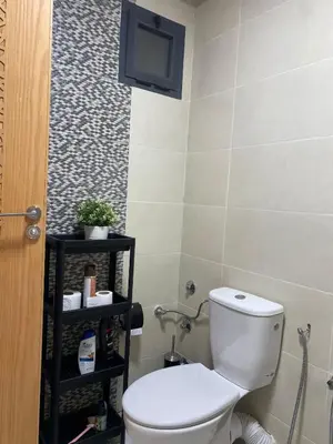 a bathroom with a toilet and a tv on the wall at Apartment in Bouznika with pool in Bouznika