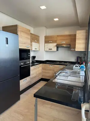 a kitchen with a black refrigerator and wooden cabinets at Séjour Premium Casablanca in LʼOasis