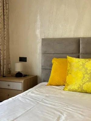 a bed with a yellow pillow and a night stand at Séjour Premium Casablanca in LʼOasis