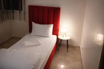 a bed with a red headboard and a table with a lamp at 3BR Authentic Apartment in the heart of Casablanca in Casablanca