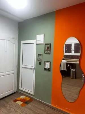 a room with an orange and green wall with a mirror at Olive & Orange Modern Studio in Rabat