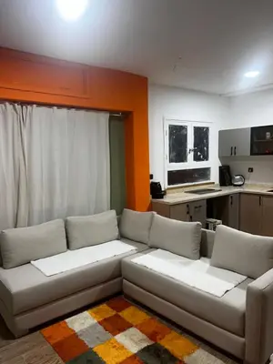 a living room with a couch and a kitchen at Olive & Orange Modern Studio in Rabat