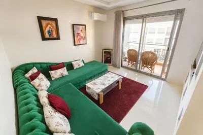 a living room with a green couch and a window at Vue Piscine Idéal pour Supporters Transfert in Mansouria