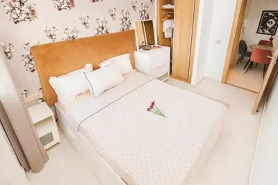 a bedroom with a white bed with a flower on it at Vue Piscine Idéal pour Supporters Transfert in Mansouria