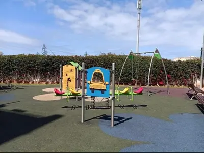 a playground with two swings and a slide at La Siesta Beach Appartement in Mohammedia