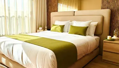 a bedroom with a large bed with two green pillows at Maya Suites - Habous Old Town - Panoramic City View in Casablanca