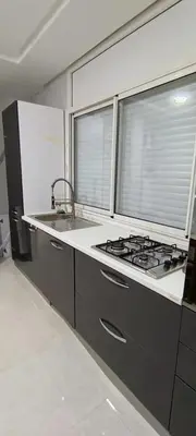 a kitchen with a stove and a sink and two windows at Temara wifak in Temara