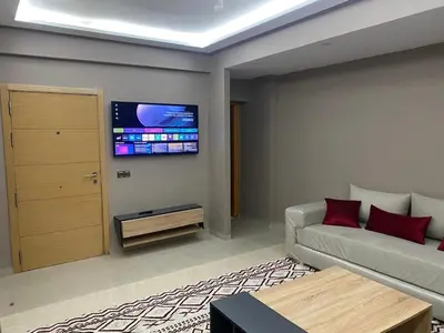 a living room with a couch and a tv on the wall at Casablanca Comfortable City-Centre Apartment in Casablanca