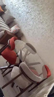 a red chair and a glass table next to a couch at Diha Appartement in Sidi Rahal
