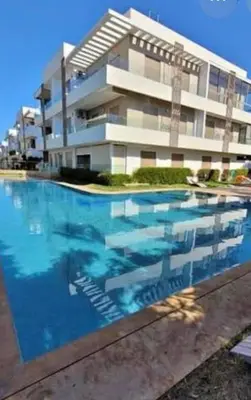 a building with a swimming pool in front of it at Diha Appartement in Sidi Rahal