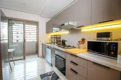 a kitchen with white cabinets and a stove top oven at Elegance - 2 bedrooms with Pool - 5 min Airport in Nouaseur