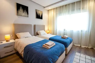 a bedroom with two beds with blue sheets and a window at Elegance - 2 bedrooms with Pool - 5 min Airport in Nouaseur
