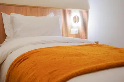 a bed with an orange blanket on top of it at Luxury 3 Suites - Av Annakhil - 5 Min to Stadium in Rabat