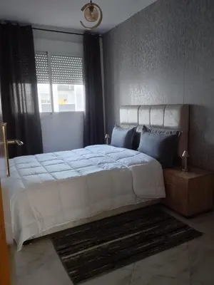 a bedroom with a large white bed with blue pillows at Comfortable Escape Stylish Apartment Quiet Residence in Oulad Kerroum