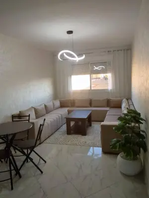 a living room with a couch and a table at Comfortable Escape Stylish Apartment Quiet Residence in Oulad Kerroum