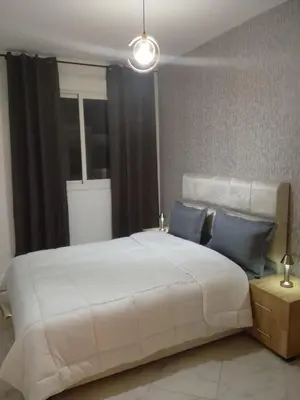 a bedroom with a large white bed with blue pillows at Comfortable Escape Stylish Apartment Quiet Residence in Oulad Kerroum