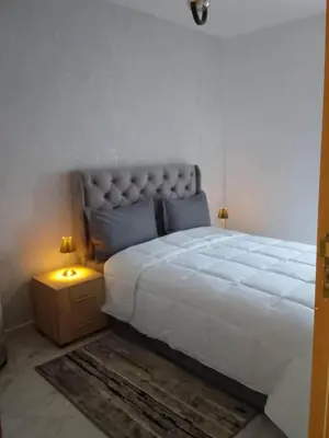 a bedroom with a large white bed and two lamps at Comfortable Escape Stylish Apartment Quiet Residence in Oulad Kerroum