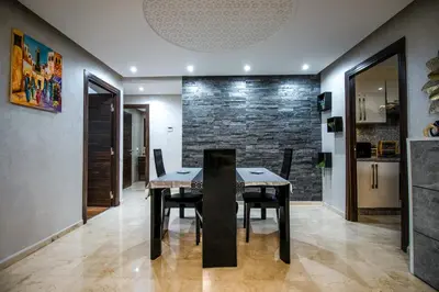 a dining room with a table and chairs and a stone wall at Forest View -3 Bedroom Apartment - Near Airport in Nouaseur