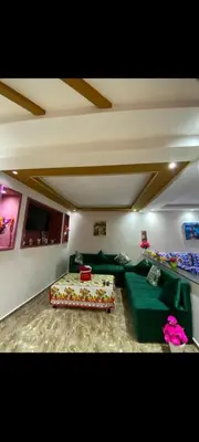 a living room with a green couch and a bed at Appartement à louer in Rabat