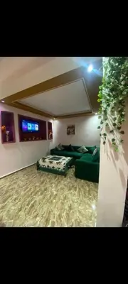 a living room with green couches and a plant at Appartement à louer in Rabat
