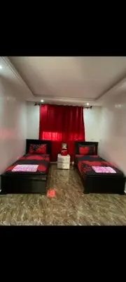 a room with two beds and a red curtain at Appartement à louer in Rabat