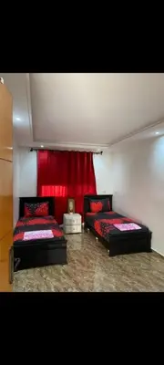 two beds in a room with a red curtain at Appartement à louer in Rabat