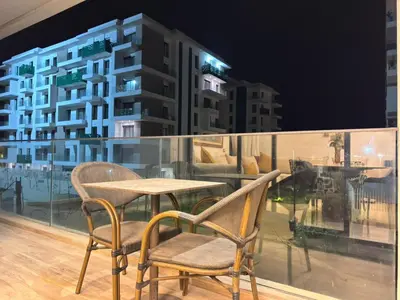 a table and chairs on a balcony at night at Furnished and bright apartment in Rabat