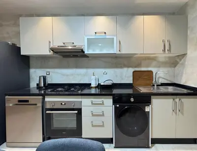 a kitchen with white cabinets and a sink and a dishwasher at Furnished and bright apartment in Rabat