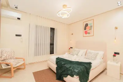 a white bedroom with a bed and a chair at New and bright stylish studio in Casablanca