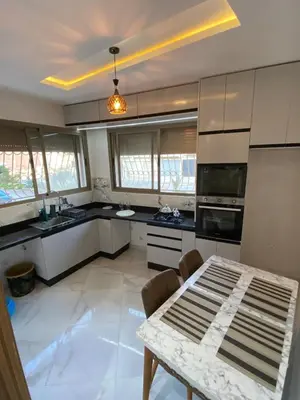a kitchen with white cabinets and a table at Sunny Cozy House Close to the Beach in Bouznika