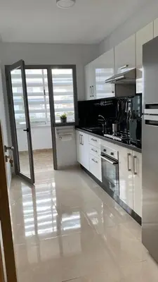 a large kitchen with white cabinets and appliances at Apparemment in Mansouria