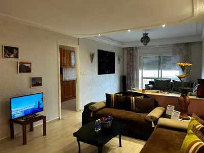 a living room with a couch and a television at Agdal Central Spacious 2BR with Terrace in Rabat