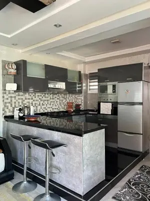 a kitchen with black counter tops and stainless steel appliances at Duplex océan harhoura avec une grande terrasse in Temara