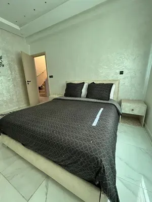 a bedroom with a large bed with a black comforter at Duplex océan harhoura avec une grande terrasse in Temara