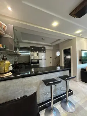 a kitchen with two bar stools in front of a counter at Duplex océan harhoura avec une grande terrasse in Temara