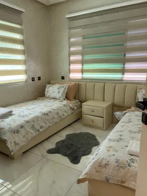 a bedroom with two beds and a rug on the floor at Duplex océan harhoura avec une grande terrasse in Temara