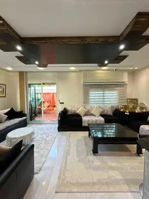 a living room with a couch and a table at Duplex océan harhoura avec une grande terrasse in Temara