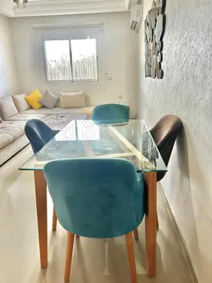 a dining room with a glass table and blue chairs at Chic 2-bedroom apartment, pool and beach 5 min away in Mohammedia