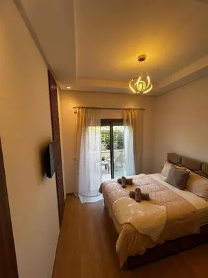 a bedroom with a large bed and a chandelier at Zen Terrace Design Studio in Zenata, WiFi & Pool in Aïn Harrouda