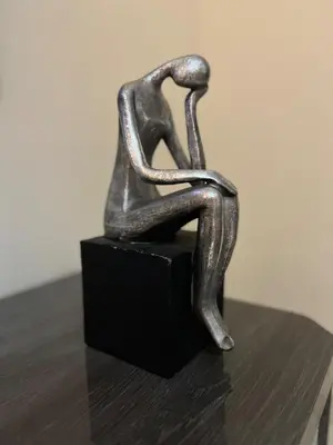 a bronze sculpture of two people sitting on a block at Studio calme Vue piscine À deux pas de la mer in Aïn Sebaa