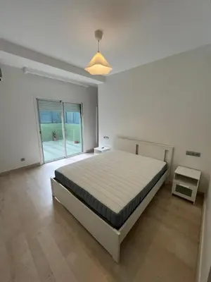 a white bedroom with a bed and a large window at Appartement 2 chambres in Casablanca
