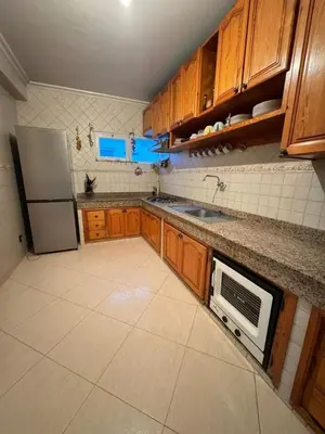 a kitchen with wooden cabinets and a white refrigerator at Comfortable apartment, Stade in Rabat