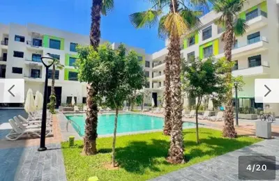 an apartment with a swimming pool and palm trees at Appartement haut standing piscine et fitness in Mohammedia