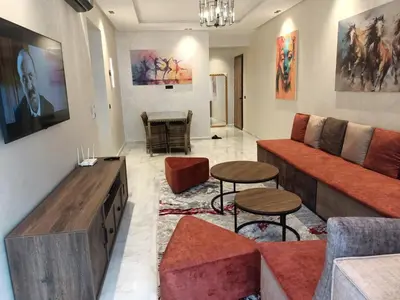 a living room with a couch and a table at Appartement haut standing piscine et fitness in Mohammedia
