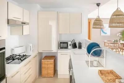 a white kitchen with white cabinets and a microwave at CFC, cozy 2 bedrooms apartment living room in Casablanca