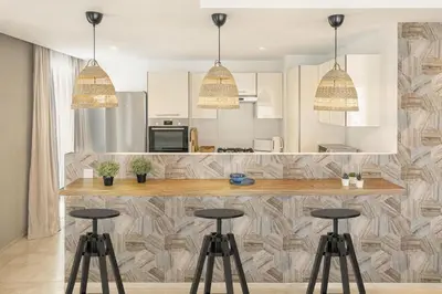 a kitchen with a counter and three stools at CFC, cozy 2 bedrooms apartment living room in Casablanca