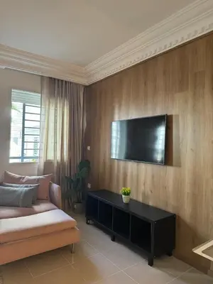 a living room with a couch and a television on a wall at Face à la Gare et au Tramway Moderne, Calme avec Resto sur place possible in Casablanca