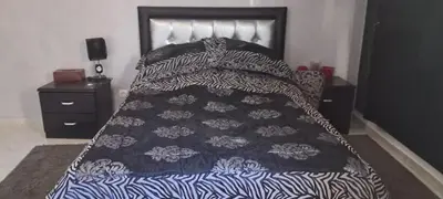 a bed with a black and white comforter on it at Appartement près de la corniche in Casablanca