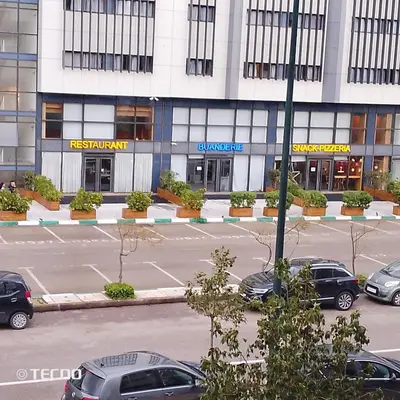 a parking lot with cars parked in front of a building at Hébergement de lux près stades in Rabat